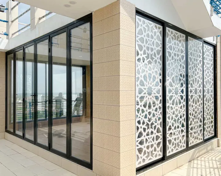 Black-framed corner glazing beside a patterned privacy screen