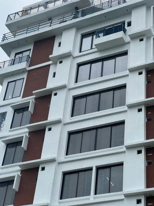 Pale building façade with repeated windows and a vertical red accent