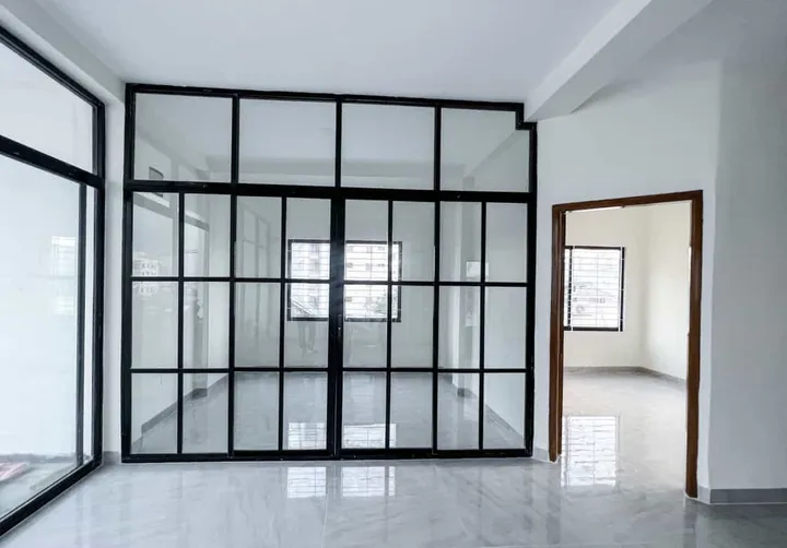 Black grid-framed glass partition and doors in a bright unfurnished room
