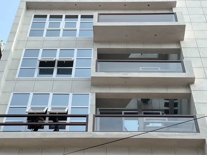 View upward at a pale building with broad horizontal windows and balconies