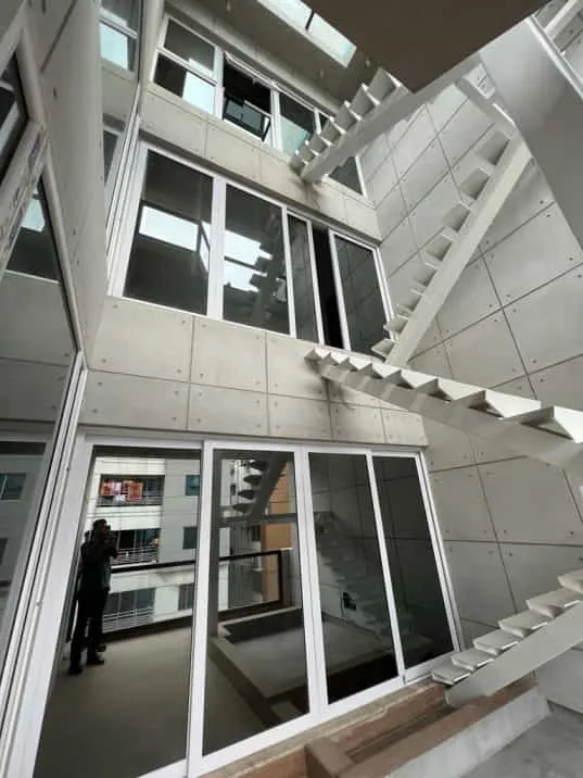Upward view of white-framed glazing and balconies around a courtyard