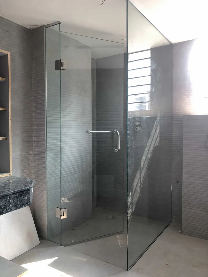Clear glass shower enclosure against dark bathroom tile