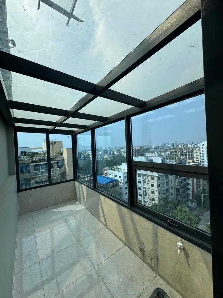 Black-framed floor-to-ceiling glazed room with tiled flooring and overhead glass