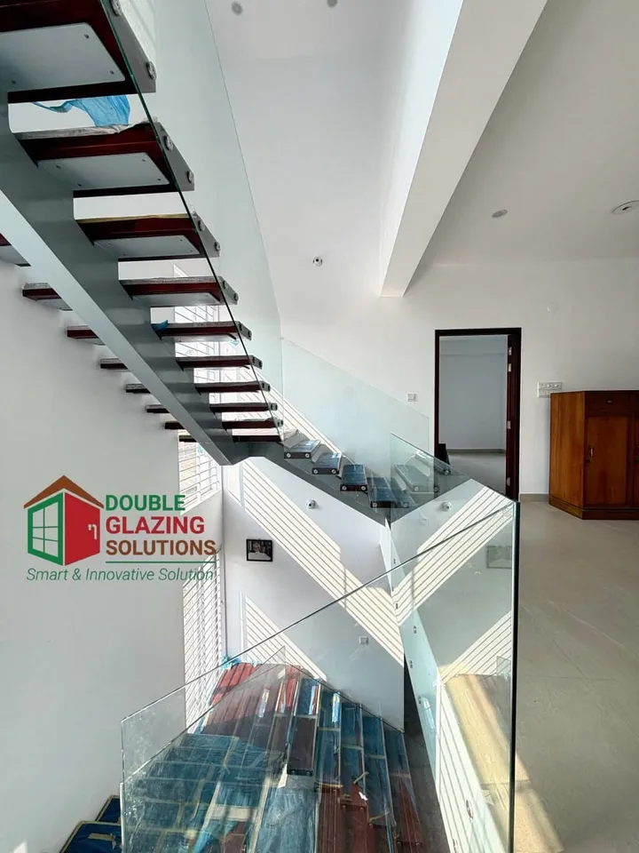 Interior stair with glass balustrade and a dark handrail