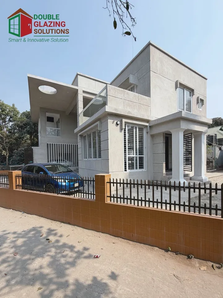 Angular pale house exterior with glass openings and a boundary wall