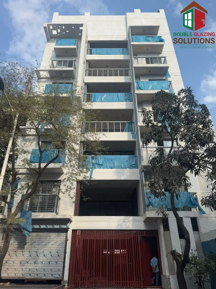 Building façade viewed through trees with glazing and red panels