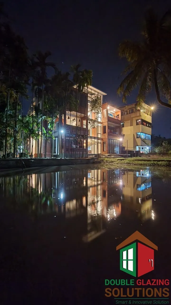 Night view of a lit glazed building reflected in water