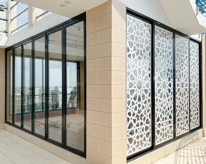 Black-framed corner windows beside a decorative pale privacy screen