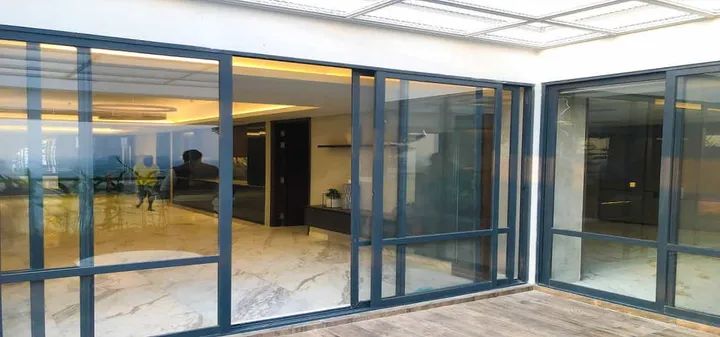 Black-framed sliding glass doors beneath a light-filled translucent ceiling